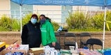 Masked volunteers standing behind a table of snacks