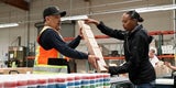 Two workers passing a stack of small boxes