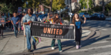 photo of people marching with a San Mateo County stands united against hate banner