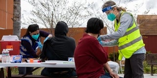 People sitting on a picnic bench being vaccinated