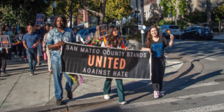 photo of people marching with a San Mateo County stands united against hate banner
