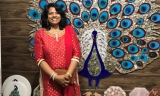 Nirmala Bandrapalli standing in front of a decorative peacock