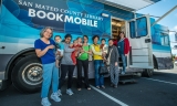 Women and children standing outside book mobile