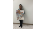 Artist Jean Polk stands with her painting, featuring an elderly lady bent over a book reading