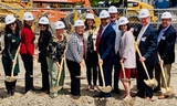 Groundbreaking ceremony attendees posed at construction site with shovels