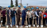 Groundbreaking ceremony attendees posed at construction site with shovels