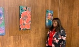 Artist Angela Holmes stands with her floral paintings