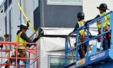 Construction workers working on side of building