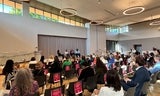 View of large room full of people seated, listening to panel