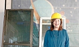 Library Director Valerie Sommer in front of colorful storybook tiles that are being protected during the renovation.