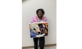 Artist stands with her painting featuring a black woman and her golden retriever