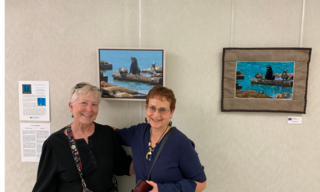 Two women smiling in front of paired artworks of seals
