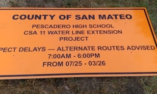 View of a road sign on the ground announcing the Pescadero High School CSA 11 construction project