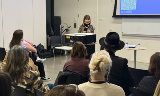 woman speaking behind sitting audience
