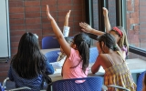 A table of children raising their hands