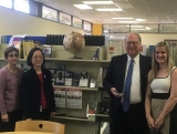 Four people pose for a photo in front of a bookshelf