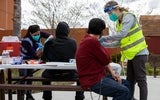 People sitting on a picnic bench being vaccinated