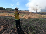 Firefighter in field with smoke in the background