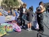 woman hands girl a backpack