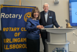 Man and woman in front of Rotary banner