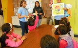 Healthy Living Ambassadors Ryezelle Felix (left) and Heather Remo (center) encourage the children to talk about their favorite foods as program coordinator Phil Minnick displays the building blocks of a healthy meal. 